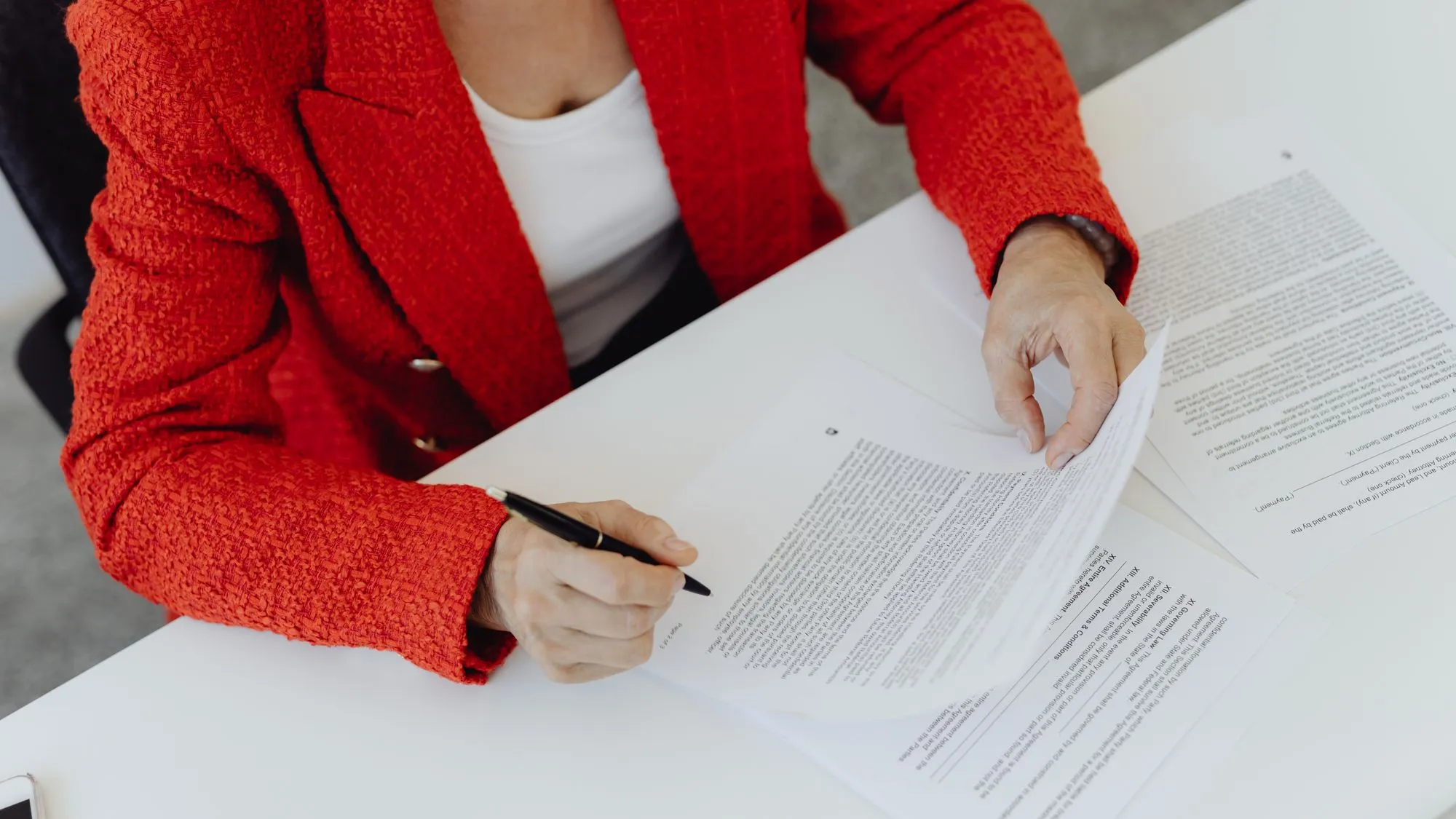Une personne signe un contrat sur un bureau, vue de dessus