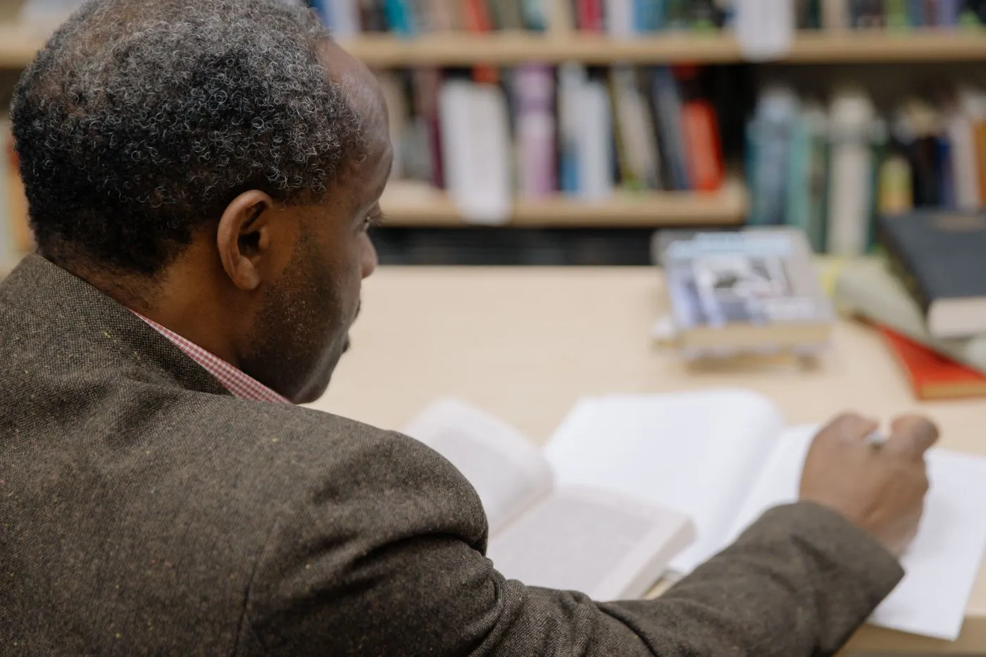 Un homme étudie un livre et prend des notes dans une bibliothèque