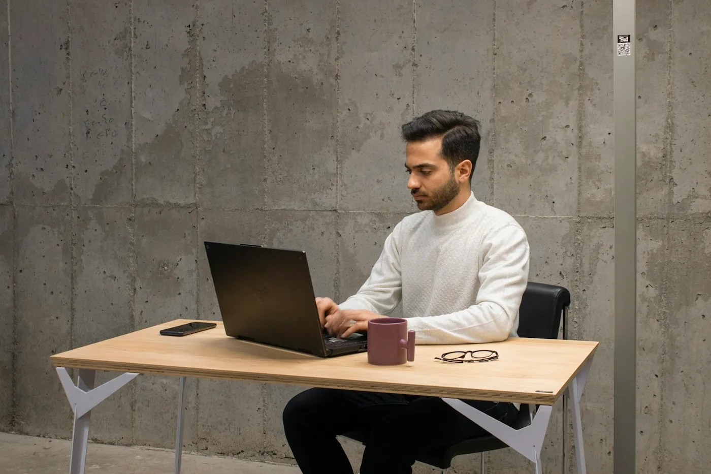 Un homme travaille seul sur son ordinateur portable à un bureau en bois