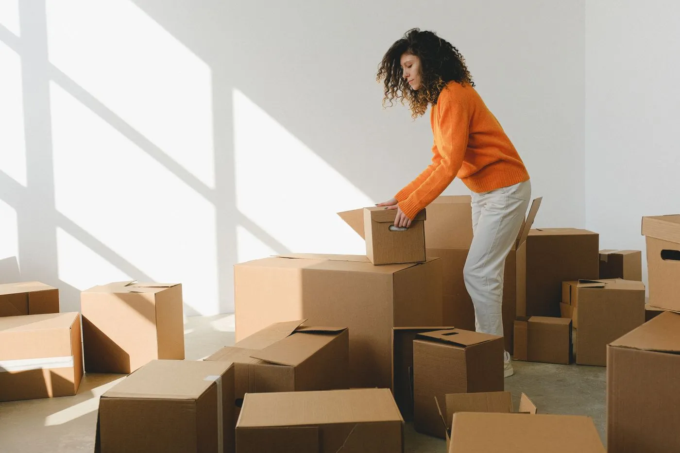 Une femme range des cartons dans une pièce vide et lumineuse