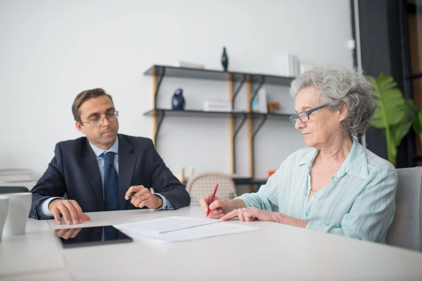 Un conseiller et une cliente relisent des documents ensemble à une table de bureau