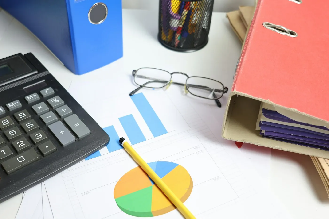 Une calculatrice, des lunettes et des graphiques imprimés sur un bureau