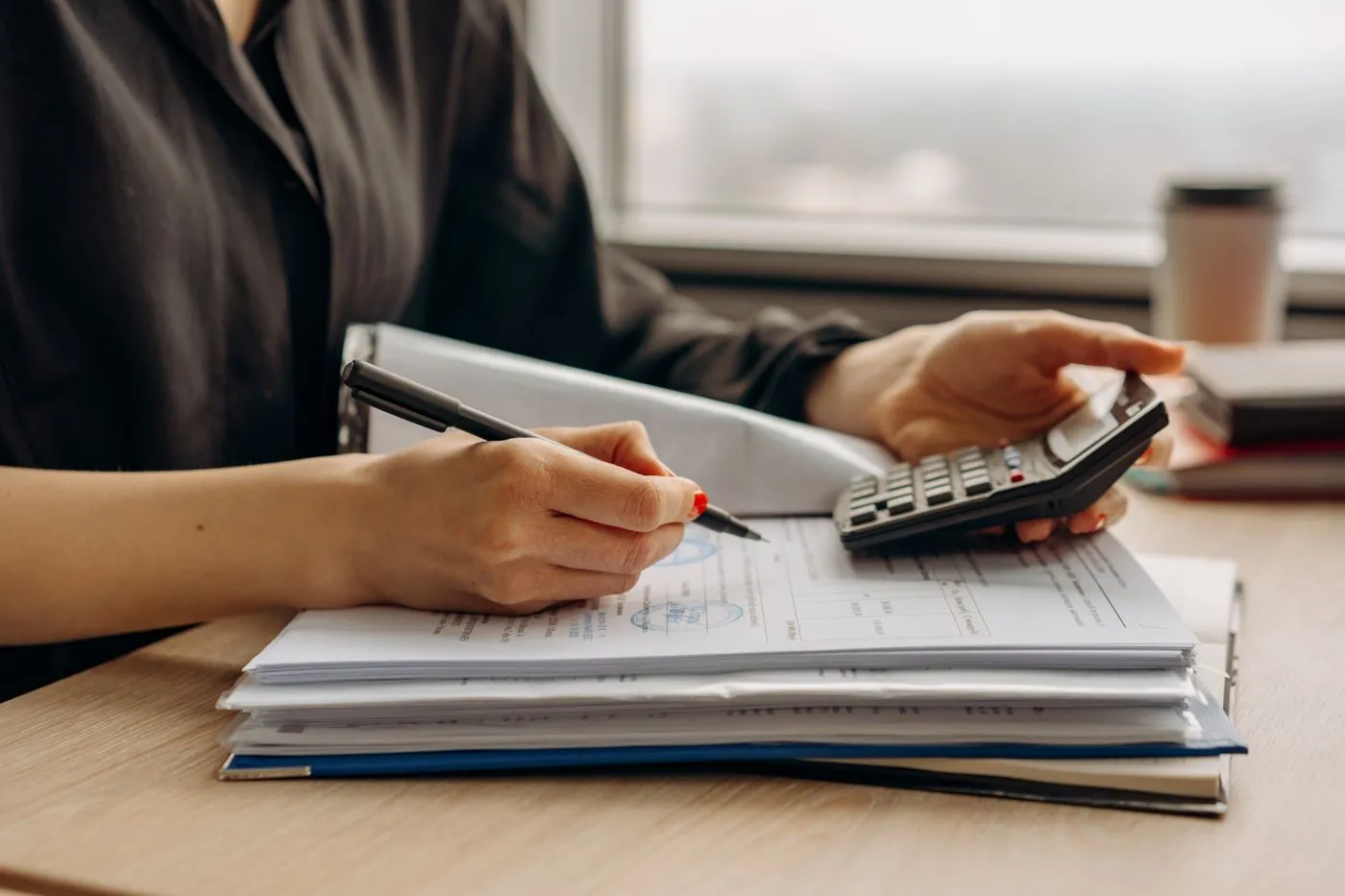 Une personne annote des documents tamponnés, une calculatrice à la main